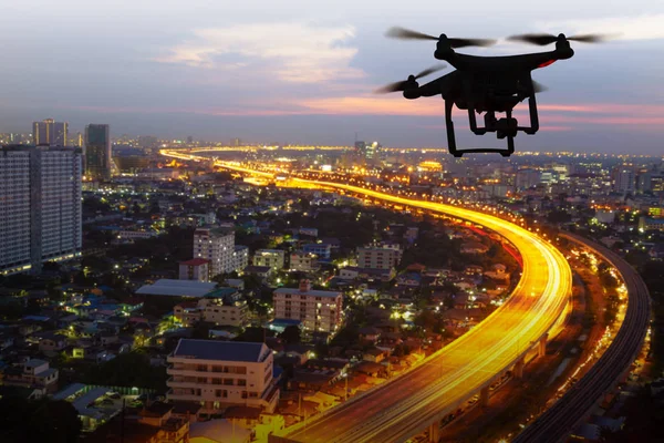 Silueta de dron volando sobre la ciudad al atardecer — Foto de Stock