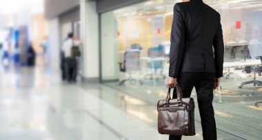 Bir evrak çantası'nı modern bir ofiste tutan işadamı