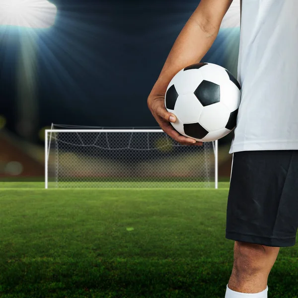 Футболіст тримає м'яч у футбольному полі — стокове фото