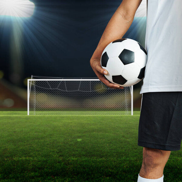 Soccer football player holding a ball in a football field