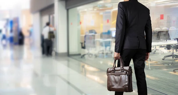 Businessman holding a briefcase in a modern office — Stock Photo, Image