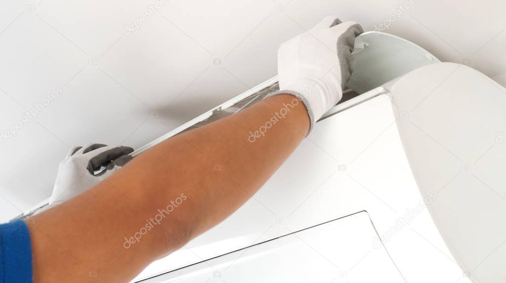 Hand of technician cleaning air conditioner in house