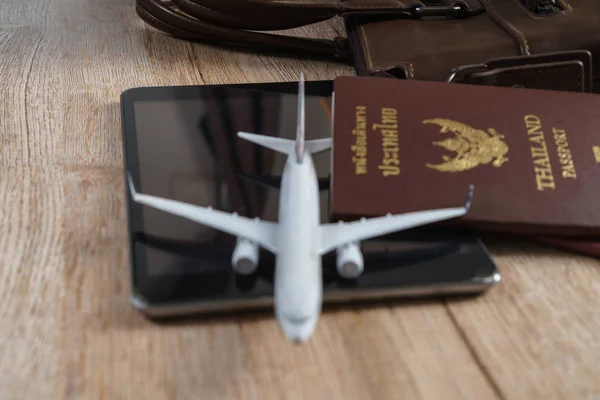 Modelo de avión pequeño, pasaporte tailandés, bolsa de cuero, tableta de madera — Foto de Stock