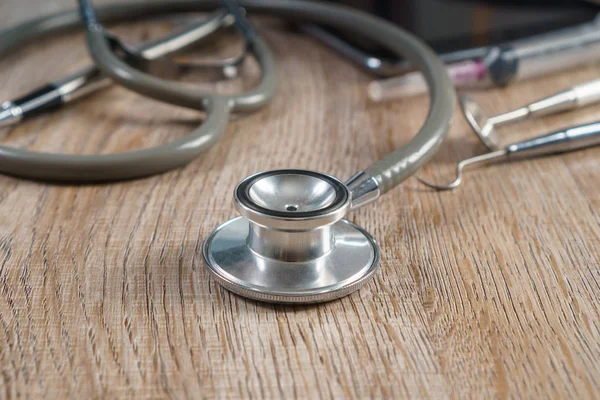 Stethoscope with syringe, pen, tablet and dental tools on wooden — Stock Photo, Image