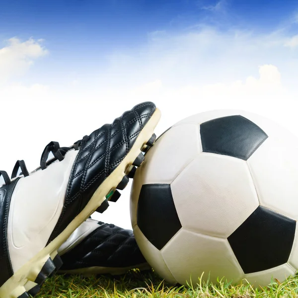 Soccer ball and shoes on grass — Stock Photo, Image