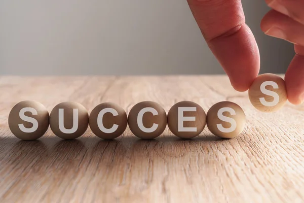 Hand putting on success word written in wooden ball — Stock Photo, Image