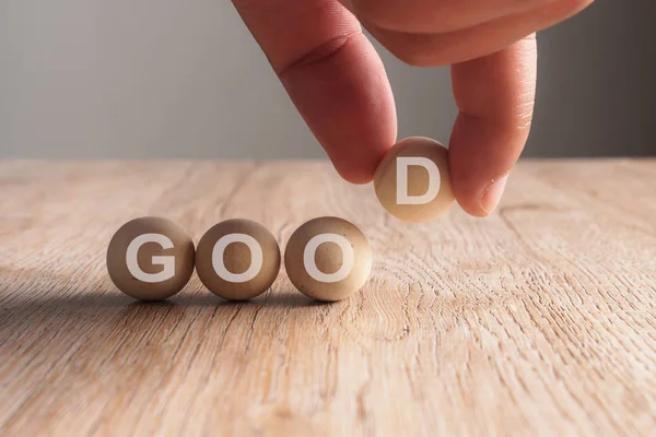 Mão colocando boa palavra escrita em bola de madeira — Fotografia de Stock