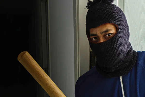 Masked robber with baseball bat hiding behind the door — Stock Photo, Image