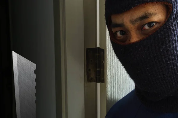 Masked robber with knife hiding behind the door — Stock Photo, Image