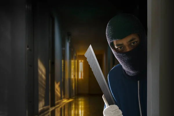 Маска грабіжник з ножем ховається за дверима — стокове фото