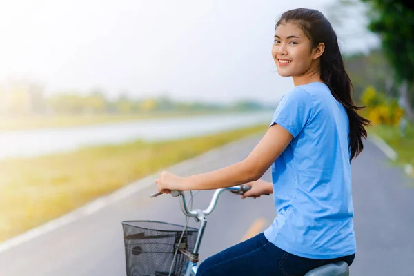 Flicka med cykel, kvinna som rider en cykel på väg i en park — Stockfoto