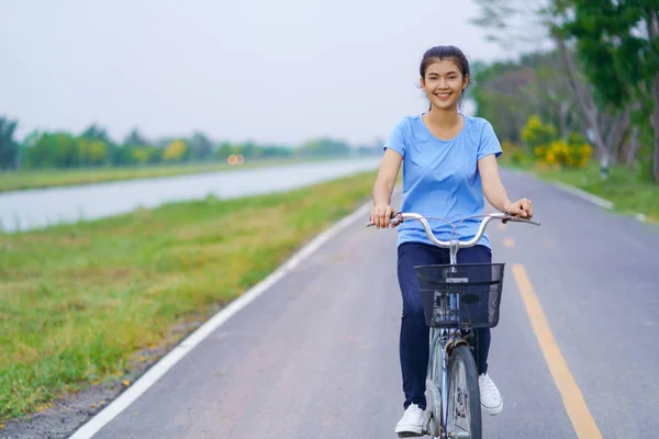 Flicka med cykel, kvinna som rider en cykel på väg i en park — Stockfoto