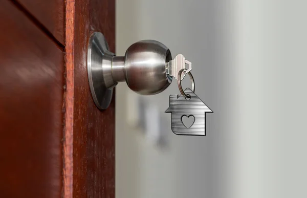 Puerta abierta con llaves, llave de la casa en el ojo de cerradura con la casa pequeña — Foto de Stock