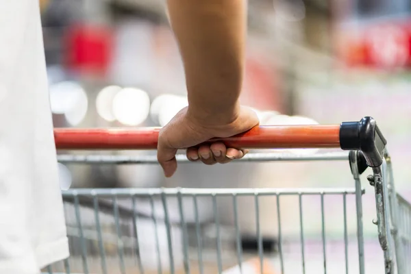 Primer plano del hombre empujando el carrito de la compra en un supermercado —  Fotos de Stock