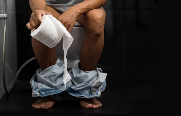 Man holding tissue roll in toilet of his house — Stock Image Man holding tissue roll in toilet of his house Stock Picture