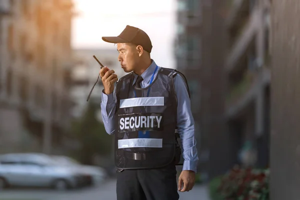 Bezpečnostní muž stojící venku pomocí přenosného rádia — Stock fotografie