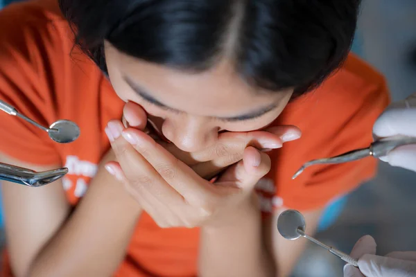 Close up of Girl frightened by dentists covers her mouth in dentist office