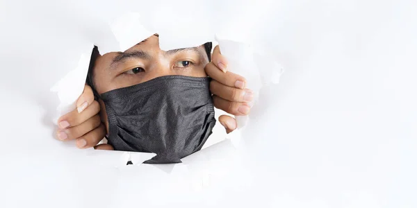 白い紙の後ろにコロナウイルスに対する保護顔マスクを身に着けている男のクローズアップ肖像画 — ストック写真