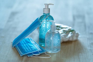 Alkol jeli el dezenfektanı ve sağlık maskesi evdeki masa arkasında.