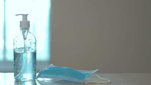 アルコールジェルハンドサニタイザーと自宅でテーブルの上の医療マスク コロナウイルスの清潔な手の衛生上の予防 流行時Covid スライダーショット — ストック動画