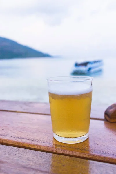 Szklankę zimnego piwa na stole w pobliżu plaży — Zdjęcie stockowe