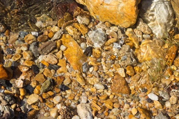 Красочные камешки под водой на заднем плане — стоковое фото