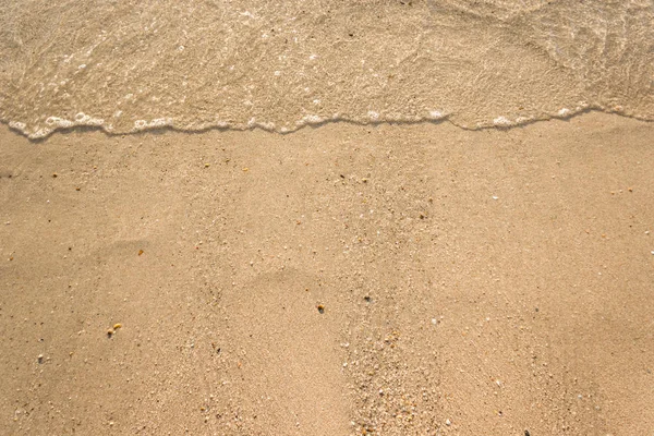 Mjuka vågor med skum av havet på sandstrand bakgrund — Stockfoto