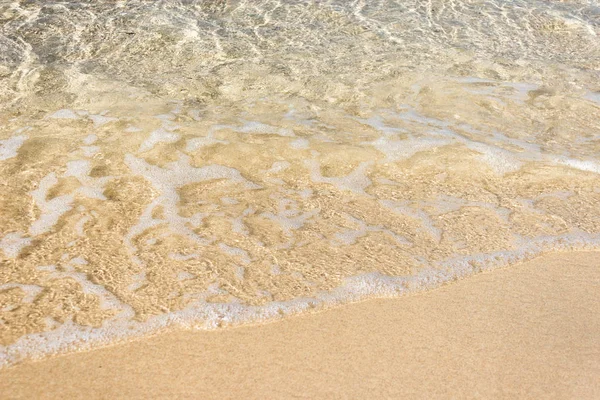 Zachte golven met schuim van de oceaan op het zandstrand achtergrond — Stockfoto