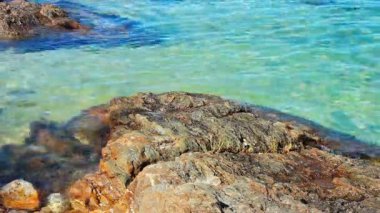 Plaj ve turkuaz yumuşak dalga deniz yakınındaki taş.