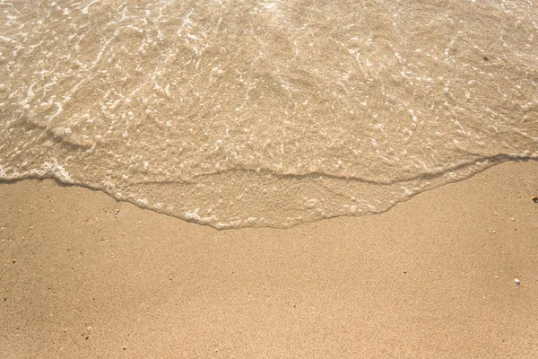 Mjuka vågor med skum av havet på sandstrand bakgrund — Stockfoto