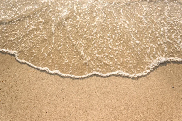 Zachte golven met schuim van de oceaan op het zandstrand achtergrond — Stockfoto