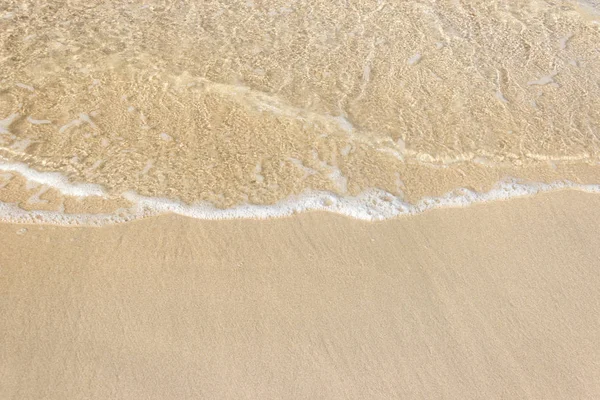Zachte golven met schuim van de oceaan op het zandstrand achtergrond — Stockfoto