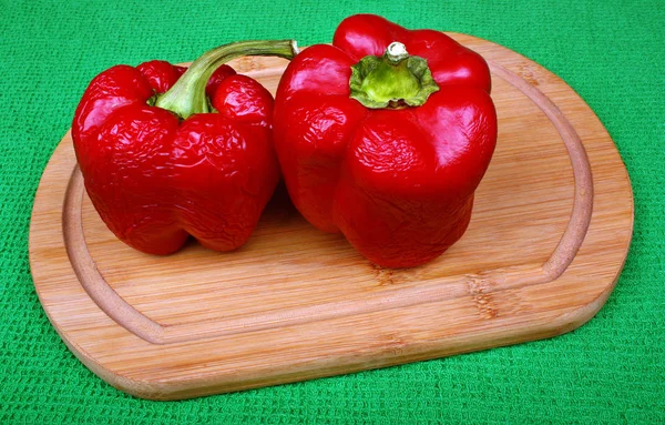 Dos pimientos rojos arrugados en una tabla de madera — Foto de Stock