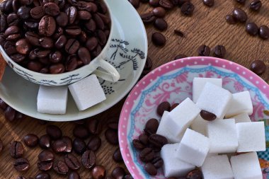 Kahve çekirdekli klasik kahve fincanı, şeker küplü çay tabağının yanında.