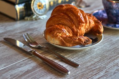 Çatal ve bıçakla uçan dairede iştah açıcı kruvasan.