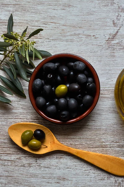 Clay bowl with black olives and wooden spoon