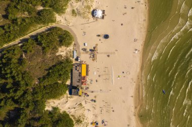 Kumlu bir plaja çarpan dalgaların yukarıdan aşağı görüntüsü.