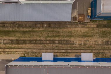 Eski ve emekli tren raylarının ve etrafındaki yeni endüstriyel kompleksin insansız hava aracı görüntüsü. Tam üstte.