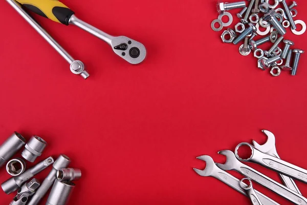 Farklı anahtarların şablonu ve kırmızı zemin üzerinde civata ve fındık yığını, ortadaki üst görünümde kopyalama alanı, düz yatıyordu