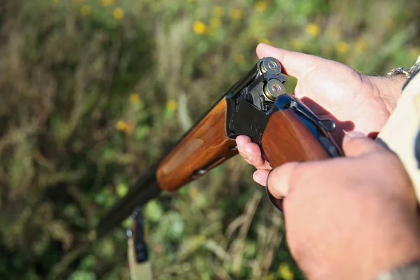 hunter holding a gun close up. a mans hand loads a bullet in a gun