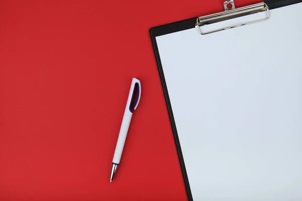 clipboard with empty paper and pen on red background