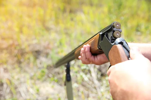 hunter holding a gun close up. a mans hand loads a bullet in a gun