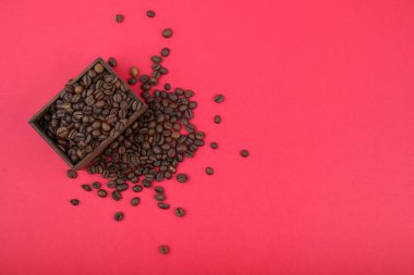 Kırmızı arka plandaki ahşap bir kutuda kahve çekirdekleri.