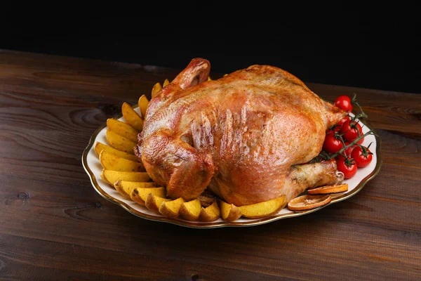 Ahşap bir yüzeyde, fotokopi alanı olan bir tabakta pişmiş tavuk. Koyu arkaplanda kızarmış tavuk.