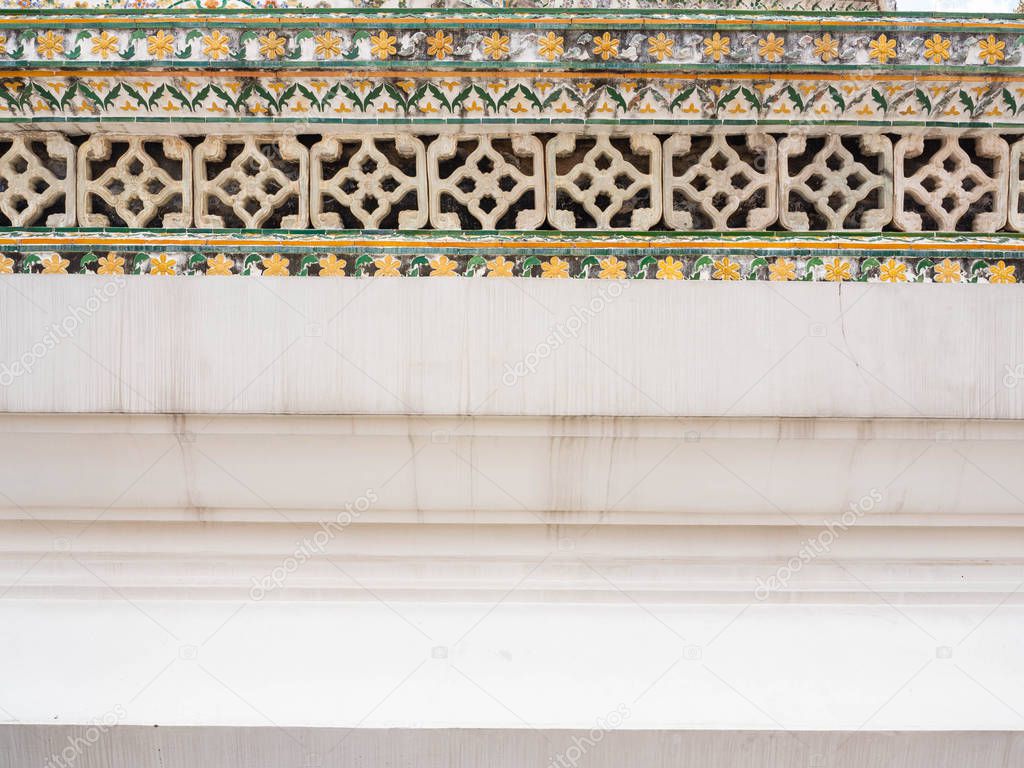 Cement fence painted white and stick tiles Multi color to prevent theft,In temple name is Wat Arun Ratchawararam Woramahaviharn at Bangkok Thailand