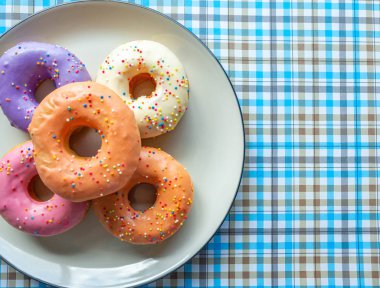 Donutlar çeşitli renklerde turuncu beyaz pembe, yüksek enerji gıdaları ve sağlıklı oranlar, tatlı aromalı şekerler, eşleştirme arka planı