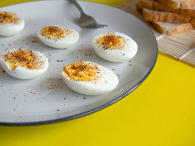 Haşlanmış yumurta, beyaz bir tabakta Cayenne biberi ve tuz, yumurta rengi beyaz ve sarı, ekmekle ye.