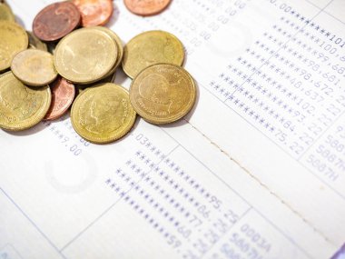 Tayland Baht Sikkeleri, banka hesap defterindeki dağlardaki altın renkleri Tayland para birimidir. İş harcamaları için, madeni para bir kavanoz para tasarrufu, beyaz arka plan