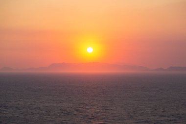 Dağların ve denizin üzerinde dramatik bir gün batımı. Yunanistan, Rodos