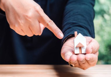 Satın almak için ev modelini gösteren bir adamın elini kapat.